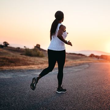 adult woman running on road at sunset