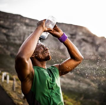athlete splashing himself with water from his water bottle